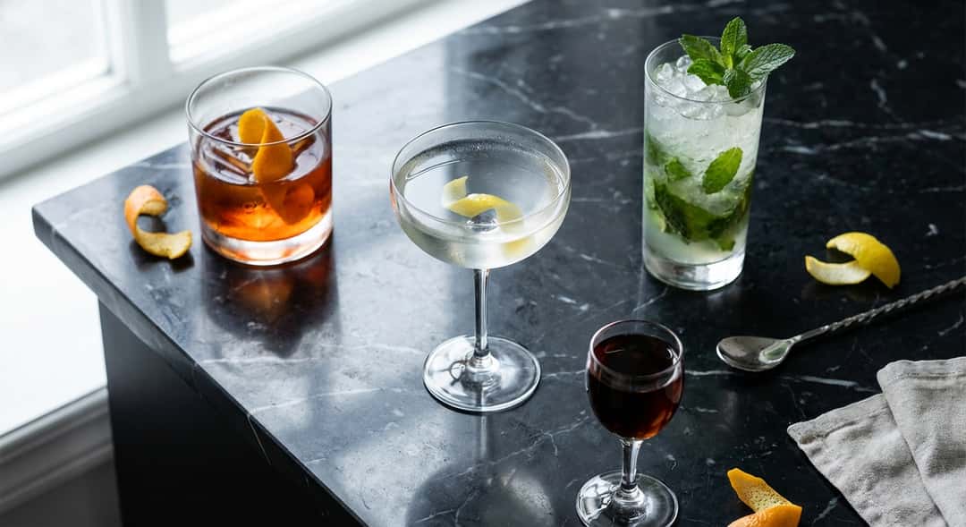 Neljä erilaista cocktailia eri laseissa – Negroni tumblerissa, Martini coupelasissa, Mojito highball-lasissa ja sherry coupessa