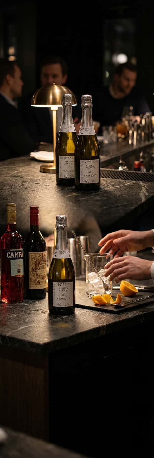 Kaksi proseccopulloa keittiötasolla Camparin ja vermutin kanssa, valmiina Negroni Sbagliaton valmistamiseen (Albino Armani Prosecco)