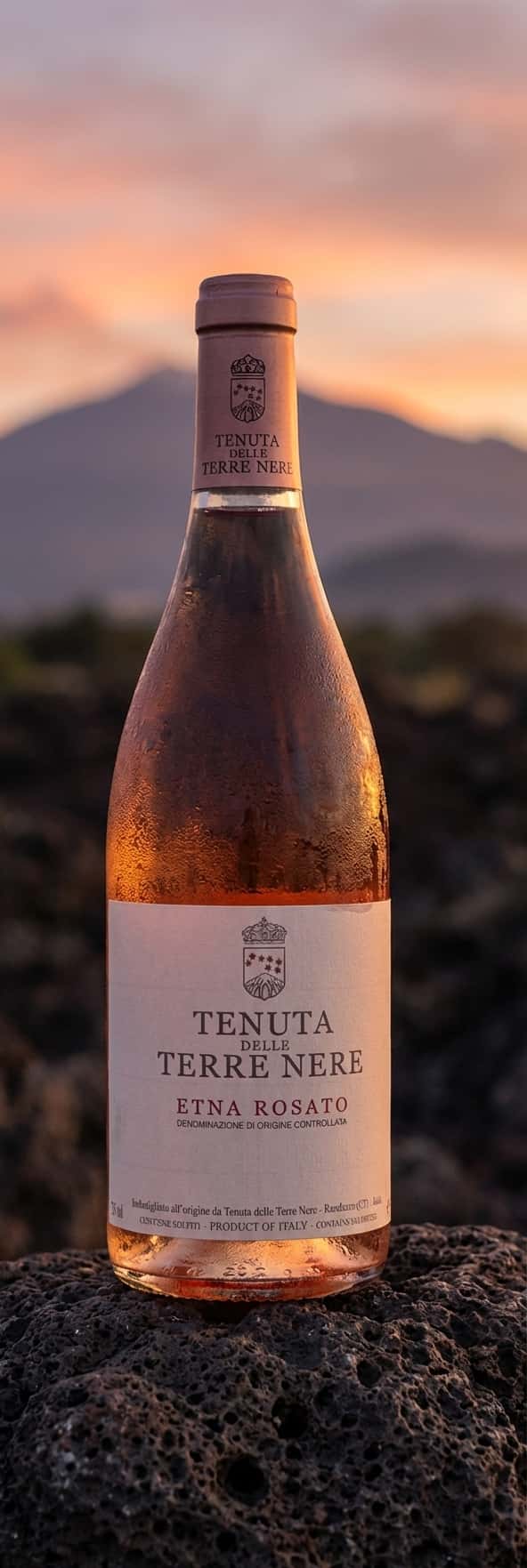 Pullo Tenuta delle Terre Nere Etna Rosatoa laavakivellä, Etnan siluetti taustalla, iltapunertava valo
